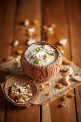 Close-up of Creamy Sabudana Kheer Garnished with dry fruits. Indian delicious dessert. Served in the coconut shell. Front view on wooden background.