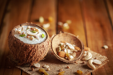 Close-up of Creamy Sabudana Kheer Garnished with dry fruits. Indian delicious dessert. Served in the coconut shell. Front view on wooden background.
