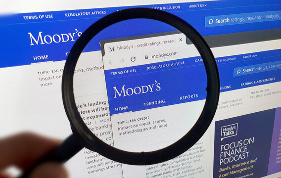 LISBON, PORTUGAL - MAY 19, 2021: Photo of Moody's homepage on a monitor screen through a magnifying glass.