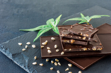 Marijuana leaves and dark chocolate on black background