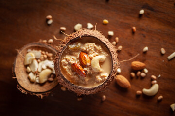 Close-up of Creamy Sabudana Kheer Garnished with dry fruits. Indian delicious dessert. Served in the coconut shell. Front view on wooden background.
