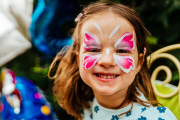 little girl having her face painted for kids party. Halloween or carnival family lifestyle Face...