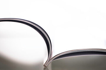 Side view of an open, beautifully curved magazine with narrow depth of field, shadow and white background