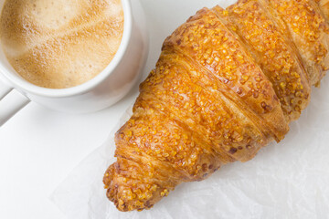 pastry croissant on white paper background with cup of coffee. French food