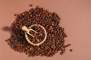 Roasted brown coffee beans on brown background. Top view. Coffee beans in a wooden scoop and bowl.