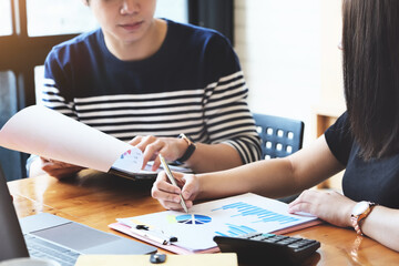 focus hand holding pen point to chart document with business woman and partnership discussion and exchange of ideas during work