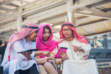 Digital marketing group arab people using smart tablet walking in  modern muslim UAE city touch screen discussion. Entrepreneur Asian people smile talking with boss outdoors