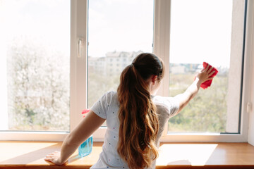 Beautiful woman cleaning window at home