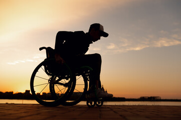 silhouette of a man in a wheelchair on the background of the sunset
