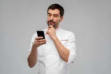 cooking, culinary and people concept - thinking male chef with smartphone over grey background