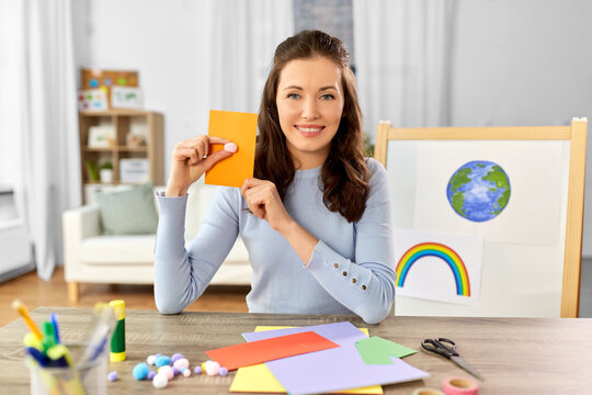 Distant Education, School And People Concept - Happy Smiling Female Teacher With Color Paper And Pompom Having Online Class Of Arts And Crafts At Home