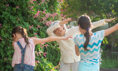 Grandchildren show their asian grandmother how to dab. Outdoors, summer