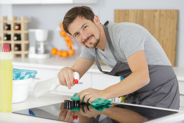 Obraz na płótnie Canvas smiling man kitchen top with spray bottle detergent
