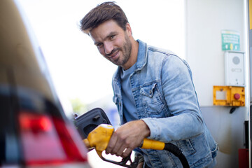 man pumping gasoline fuel in car at gas station
