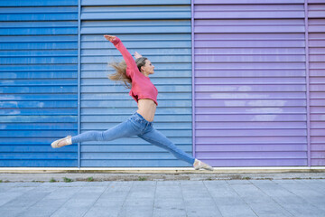 dancer woman jumping in front of a colorful wall