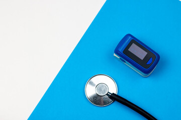 Fototapeta na wymiar Stethoscope and pulse oximetry on blue background. Pulse oximetry a noninvasive and painless test that measures oxygen saturation level. Part of set.