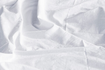 Messy bedding sheet.  Crumpled textile background. White pleated fabric.