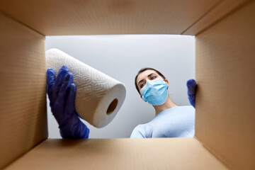 home delivery, shipping and pandemic concept - woman in protective medical mask and gloves opening...
