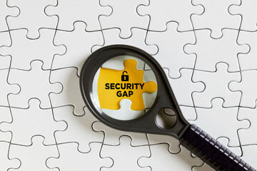 The word security gap on missing puzzle piece with a magnifying glass. To find or discover a...