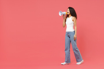 Full length young fun expressive excited happy curly african american woman 20s in white tank shirt screaming shouting loudly hot news in megaphone isolated on pink color background studio portrait.