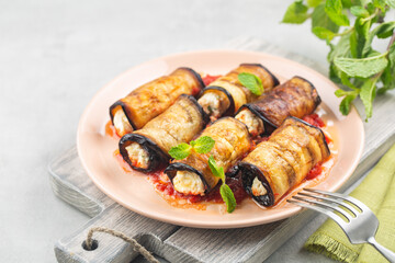 Eggplant roll ups with ricotta, parmesan cheese and tomato sauce. On light table.