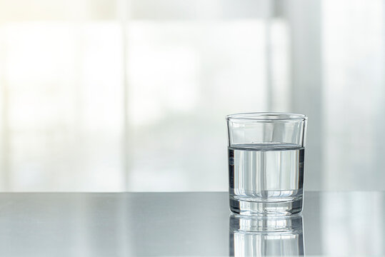 A glass cup of water on the table(desk), day light in the morning.