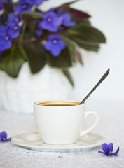 a cup of black coffee on the table with a homemade violet flower