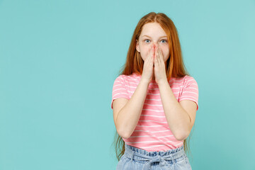 Little shocked amazed redhead kid girl 12-13 years old wearing pink striped tshirt cover mouth with hands arms isolated on pastel blue background studio portrait. Children lifestyle childhood concept