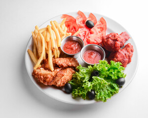 Roasted chicken wings and French fries isolated over white background. Served with fresh lettuce salad