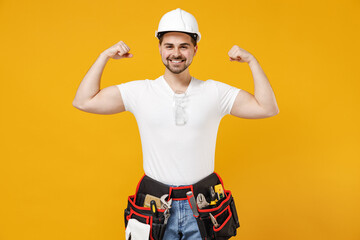 Young employee handyman man in protective helmet hardhat showing biceps hand muscles demonstrate...
