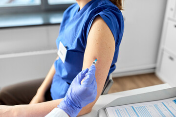 health, medicine and pandemic concept - close up of female doctor or nurse wearing protective medical gloves with syringe vaccinating medical worker hospital