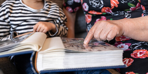 A grandmother with her granddaughter looking at a family photo album.