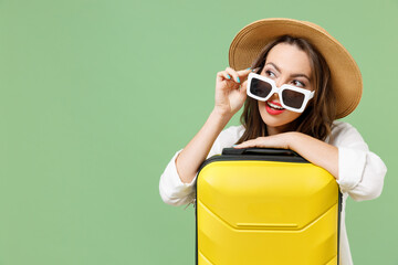 Close up traveler dream tourist woman in casual clothes hat glasses leaning on yellow suitcase...