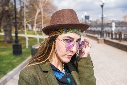 Portrait of a young and beautiful hippie girl in a hat and glasses
