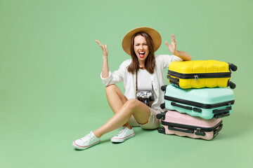 Full length angry traveler tourist woman in casual clothes hat sit at many suitcases spread arms...
