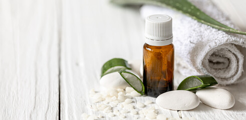 Spa composition with a jar of natural oil and aloe leaves with a towel.