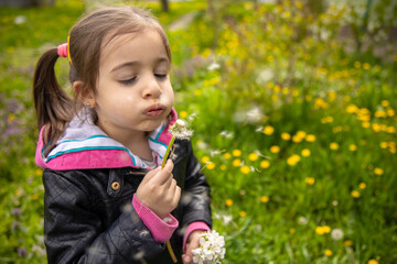 Funny child with dandelion flower in the spring park.