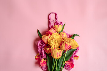 Flat lay composition with spring flowers on string bag copy space.