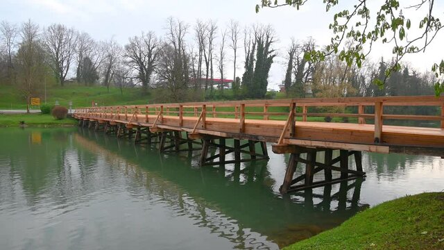 Empty wooden bridge near Otocec island in Slovenia. Calm river Krka flowing under the bridge. Handheld, wide angle, real time