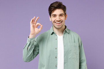 Young brunette smiling happy caucasian man 20s years old wearing casual mint shirt white t-shirt show ok okay gesture isolated on purple violet background studio portrait. People lifestyle concept