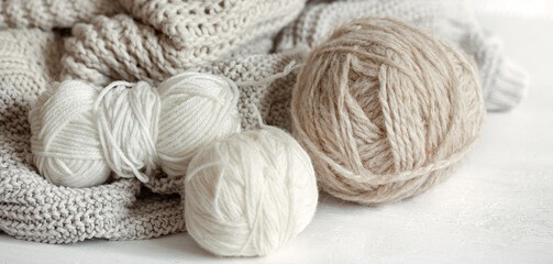 Close-up of yarn in pastel colors and knitted cozy sweaters.