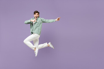 Fototapeta na wymiar Full length fun excited cool young man in casual mint shirt white t-shirt jump high point index finger aside on workspace area mock up isolated on purple violet background. People lifestyle concept