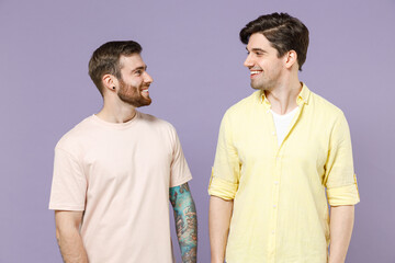 Fototapeta premium Two young smiling cheerful caucasian positive happy cool men friends together wearing casual t-shirt looking to each other isolated on purple color background studio portrait People lifestyle concept