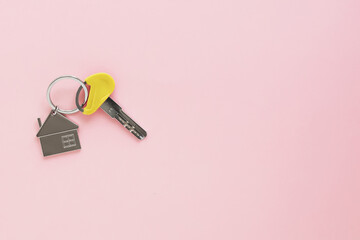 one key with house keychain on a pink background, place for text - obrazy, fototapety, plakaty