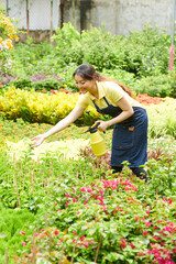 Young gardening center worker spraying plants and flowers with water