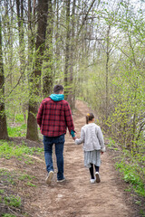 Obraz premium Little girl with dad is walking in the spring forest, holding hands.