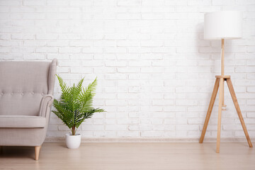 Sofa, lamp and plant over brick wall with copy space