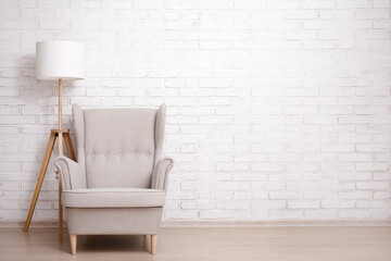 Modern armchair and lamp with copy space over brick wall