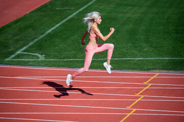 Fototapeta premium Never give up. marathon. energetic and sporty. sexy fitness woman in sportswear. athletic lady run on stadium running track. female athlete ready for sprint sport workout. trainer or coach training
