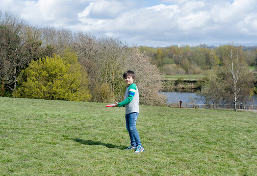 Happy kid playing in the park,Child having fun playing outside in sunny day spring,School boy have fun with flying disc in field on summer, Sport and Recreation outdoors activity for children concept